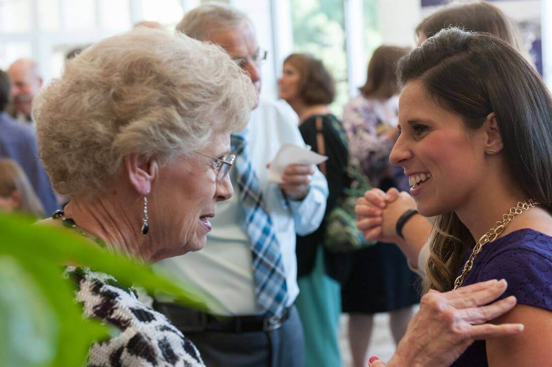 Dana Hunter at a donor event speaking with an elegantly dressed older woman.